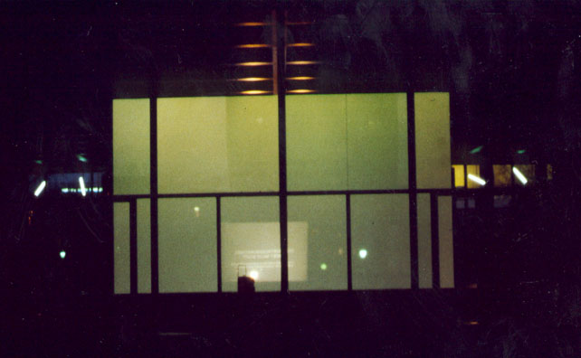 Nächtliche Ansicht großer Fensterflächen mit kleinen weißen Lichtpunkten.