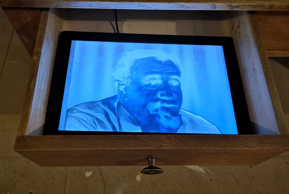 Bildschirm in einer geöffneten Tischschublade mit blau getönter Porträtaufnahme.