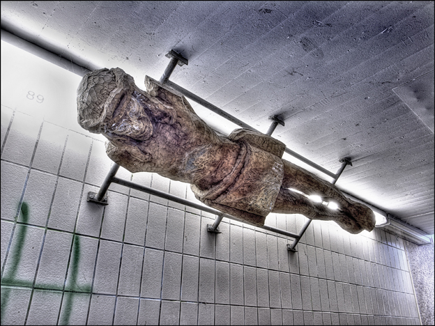 Blick von unten auf die Christusfigur, die waagerecht unter der Decke einer Unterführung befestigt ist.