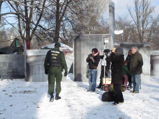Gruppe von Menschen zwischen bedruckten Architekturflächen und Säulenformen im verschneiten Park.