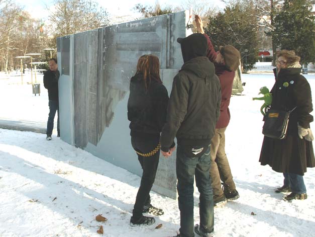 Menschen stehen vor bedruckten Architekturflächen in einem verschneiten Park.