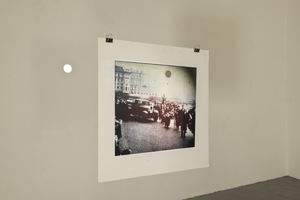 Schwarz-weiße Fotografie vor einer hellen Wandfläche mit einer kleinen runden Öffnung.