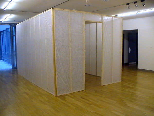 Rauminstallation aus hohen transparenten Wandflächen mit Holzrahmen auf einem Holzboden.