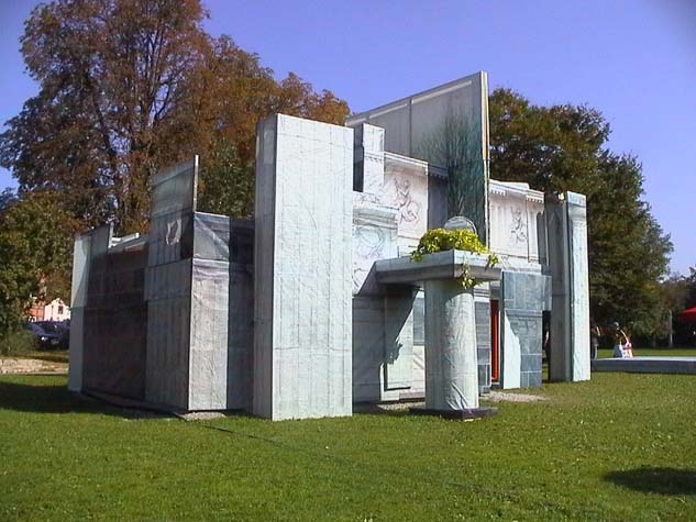 Seitliche Ansicht der gebäudeartigen Installation aus bedruckten Architekturflächen im Freien.