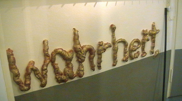 Das Wort „Wahrheit“ aus braunen plastischen Buchstaben an einer hellen Wand.