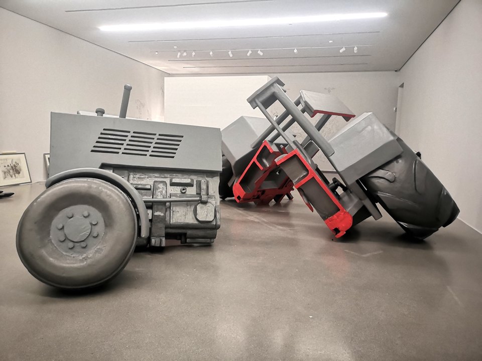 Seitliche Ansicht der beiden gekippten Traktorskulpturen im Ausstellungsraum.