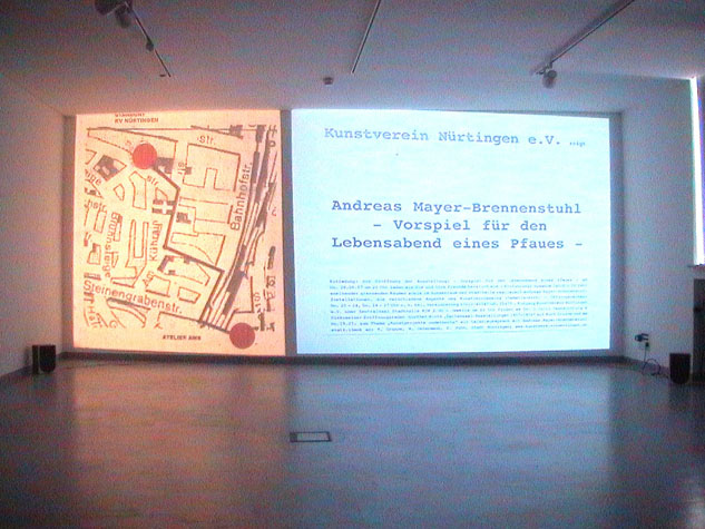 Fotografie einer projizierten Ausstellungsankündigung zu „Vorspiel für den Lebensabend eines Pfaues“ im Kunstverein Nürtingen.